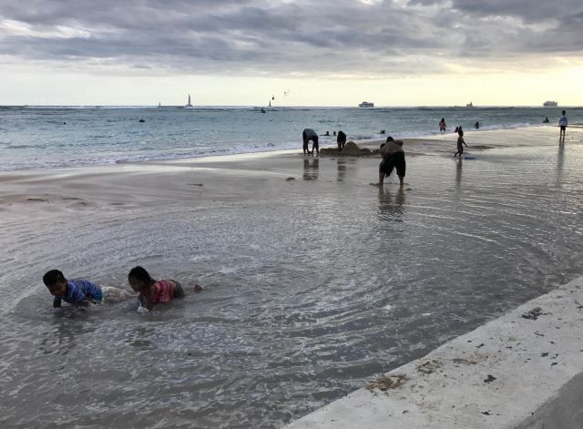 Children play on flooded Honolulu beach during record-high sea levels in 2017.
